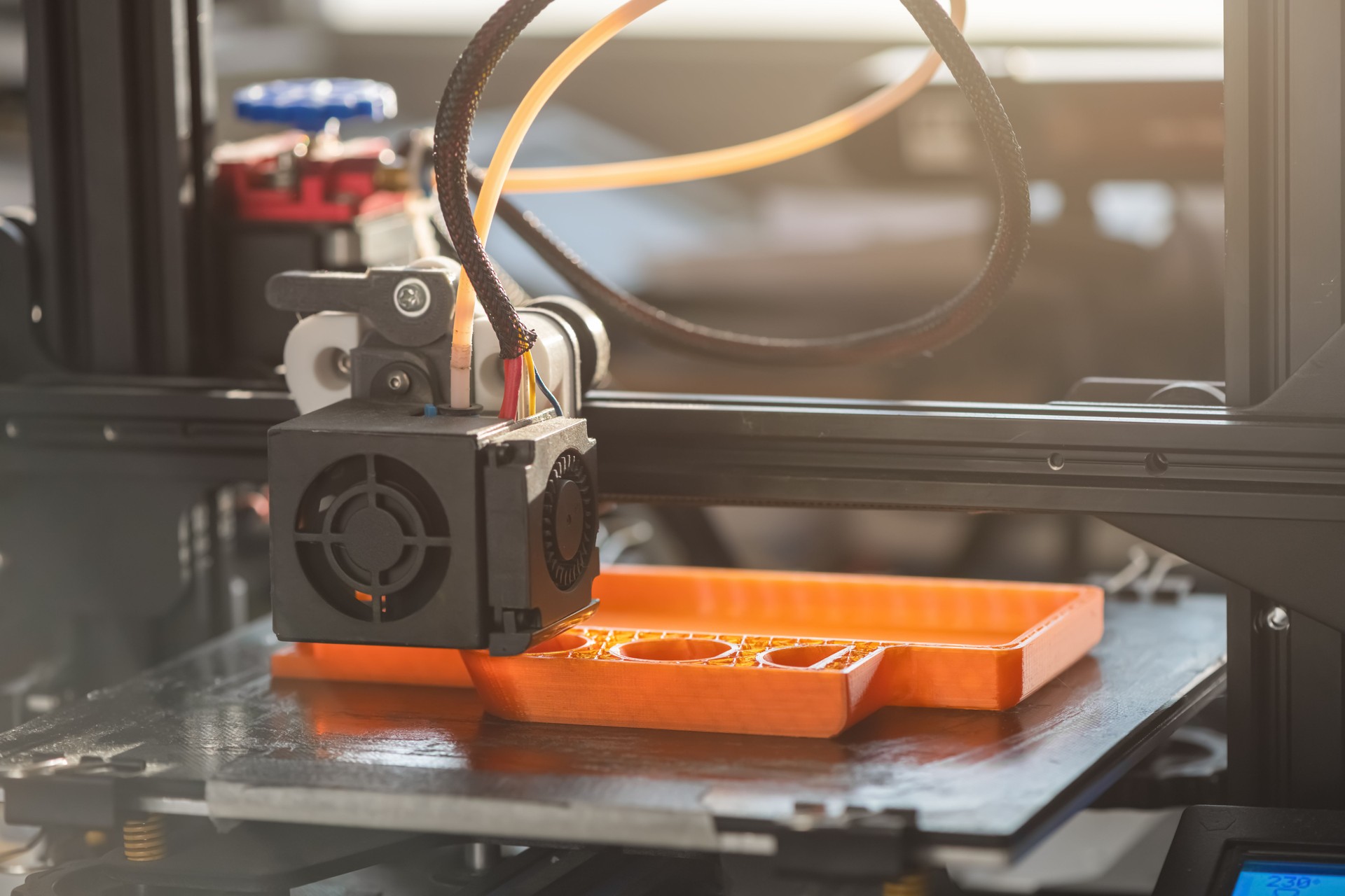 Der 3D-Drucker druckt orangefarbenes Kunststoffmodell